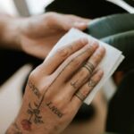 tattooed hand cleaning houseplant leaf